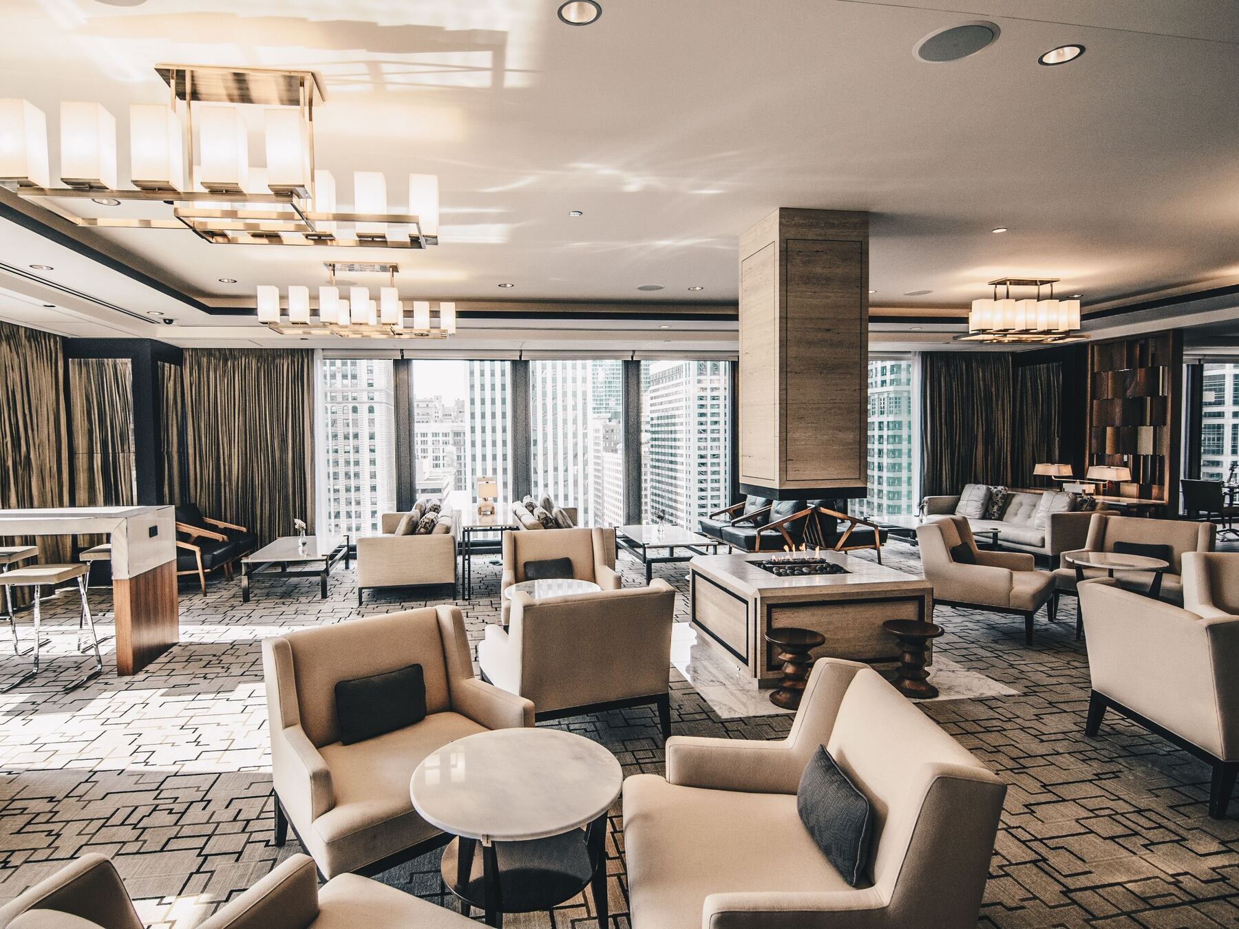 A warm, neutral lounge interior with armchairs, a stone column and timber and bronze detailing
